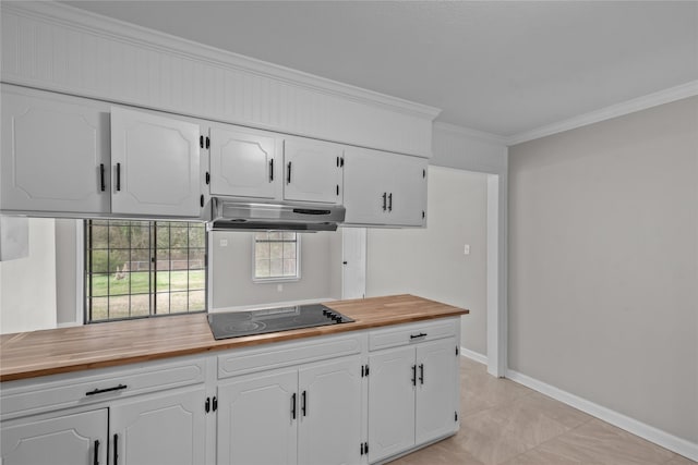 kitchen with wooden counters, ornamental molding, under cabinet range hood, white cabinets, and black electric stovetop