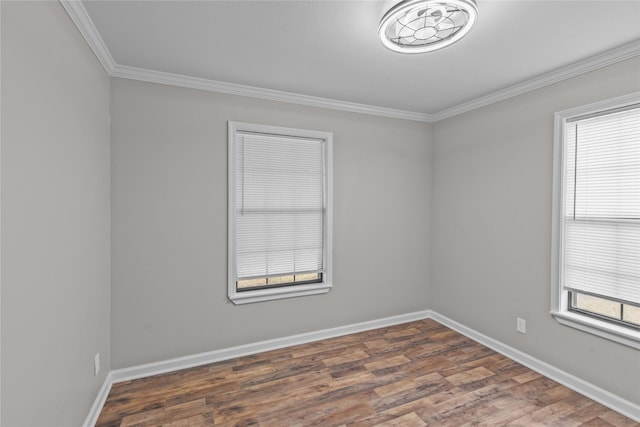 empty room with crown molding, wood finished floors, and baseboards