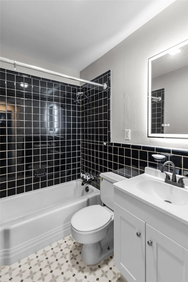 bathroom with vanity, tile walls, toilet, and tub / shower combination