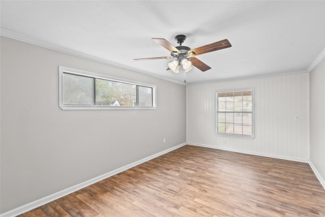 spare room featuring a ceiling fan, crown molding, wood finished floors, and baseboards