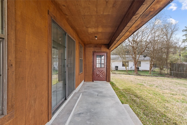 doorway to property with a patio, a lawn, and fence