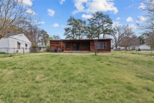 back of house with central air condition unit, a yard, and fence