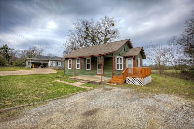 bungalow featuring driveway, covered porch, an outdoor structure, and a front yard