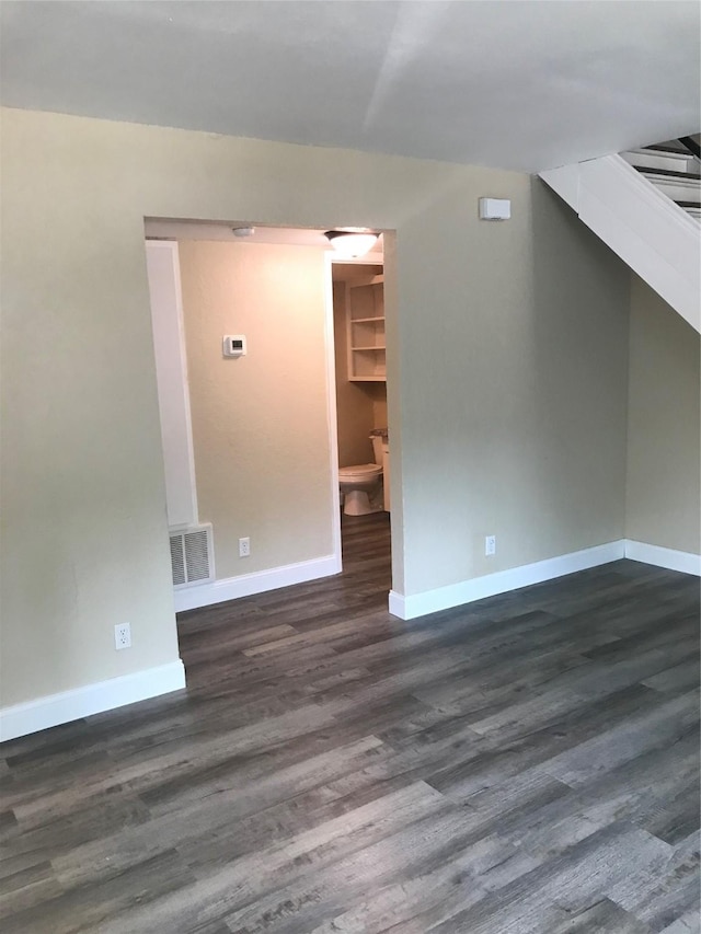 interior space with dark wood-style floors, visible vents, and baseboards