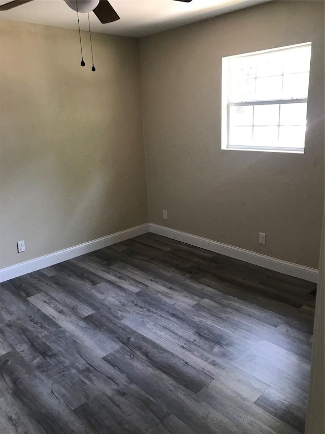 empty room featuring dark wood-style floors, a ceiling fan, and baseboards