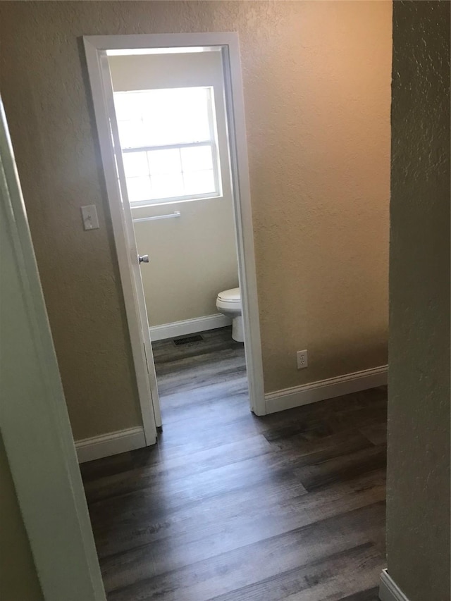 bathroom with visible vents, baseboards, toilet, wood finished floors, and a textured wall