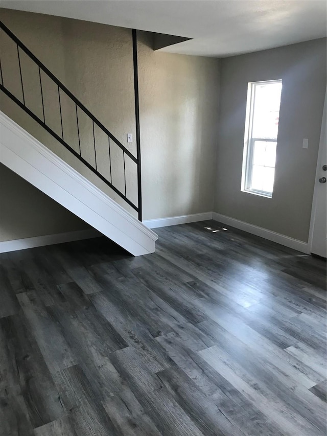 unfurnished living room with baseboards and dark wood-style flooring