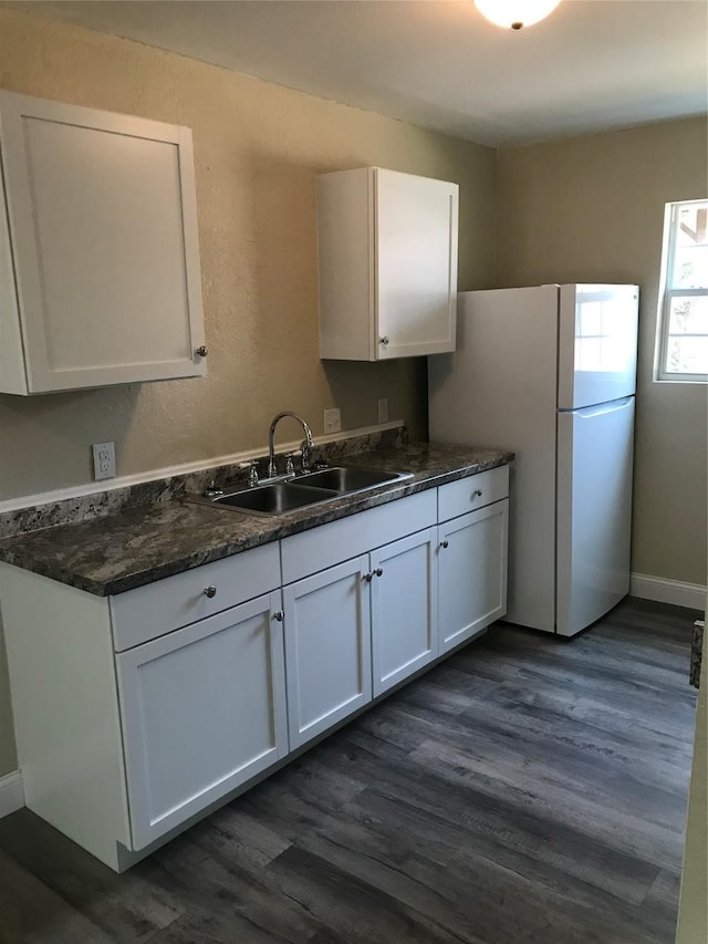 kitchen featuring white cabinetry, dark wood-style flooring, freestanding refrigerator, and a sink