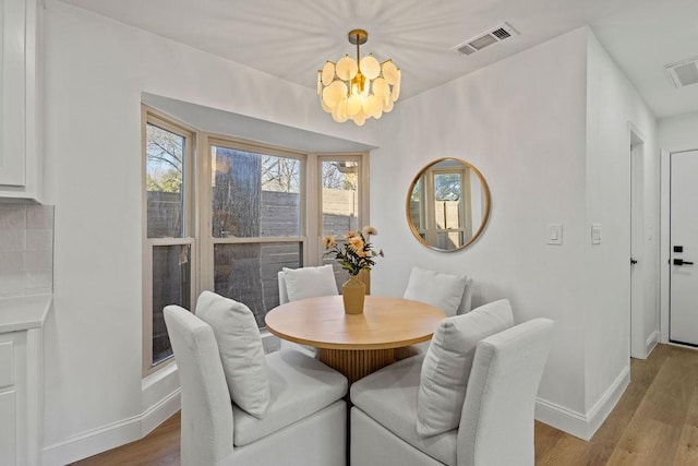 dining room with wood finished floors, visible vents, and baseboards