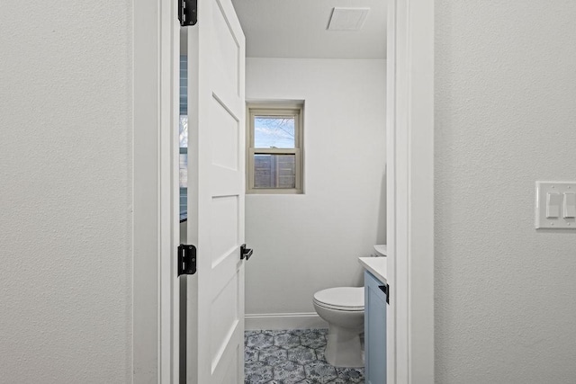 bathroom featuring toilet, vanity, and baseboards