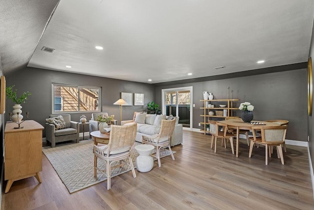 living room featuring a wealth of natural light, visible vents, baseboards, and wood finished floors