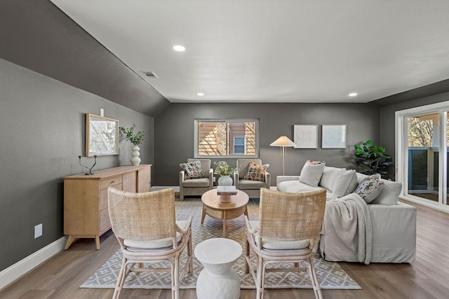 living area featuring visible vents, baseboards, light wood-type flooring, lofted ceiling, and recessed lighting