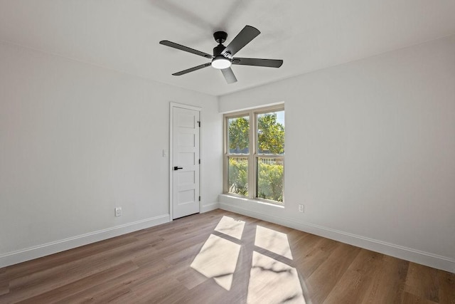 empty room with wood finished floors, baseboards, and ceiling fan