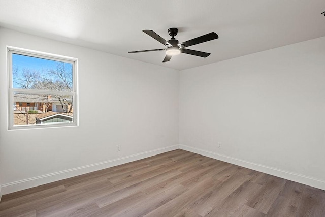 empty room with ceiling fan, baseboards, and wood finished floors