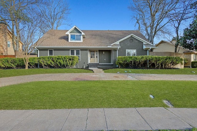 view of front of house featuring a front lawn, brick siding, and a shingled roof