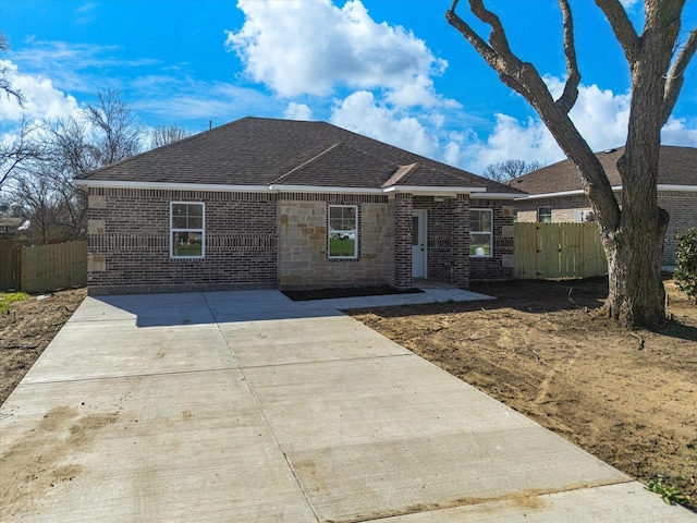 single story home featuring fence, brick siding, and a shingled roof