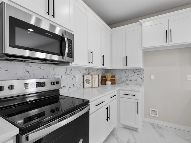 kitchen with baseboards, white cabinets, marble finish floor, appliances with stainless steel finishes, and tasteful backsplash