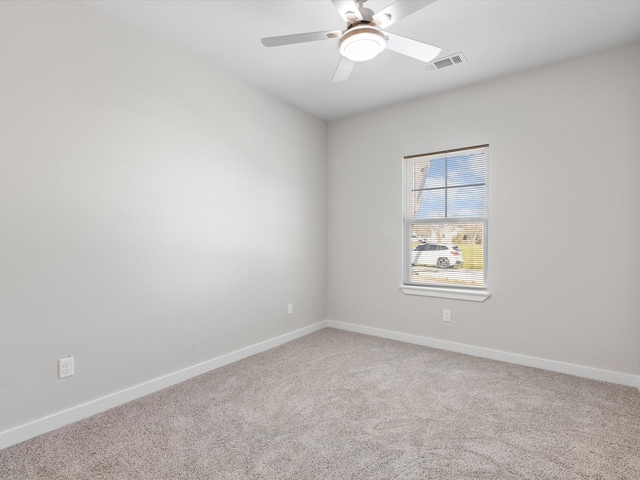 spare room with light carpet, visible vents, a ceiling fan, and baseboards