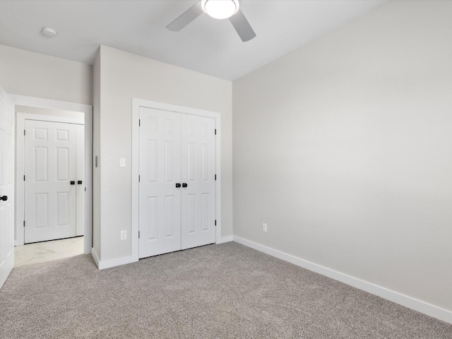 unfurnished bedroom with a closet, baseboards, light colored carpet, and ceiling fan