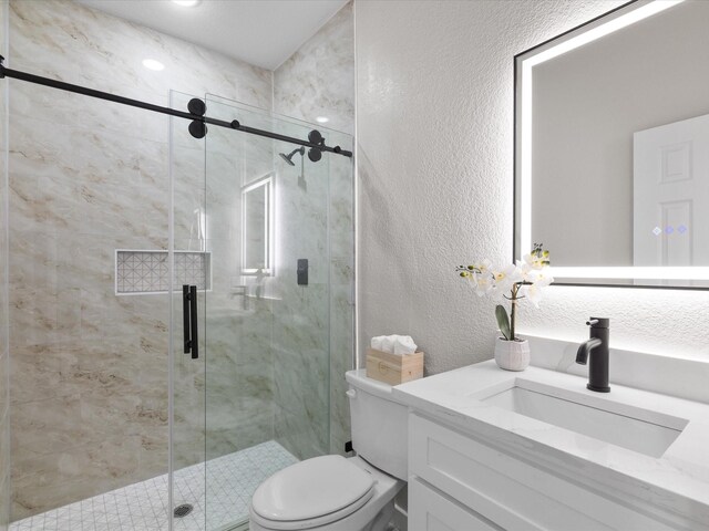 full bathroom featuring toilet, a stall shower, vanity, and a textured wall