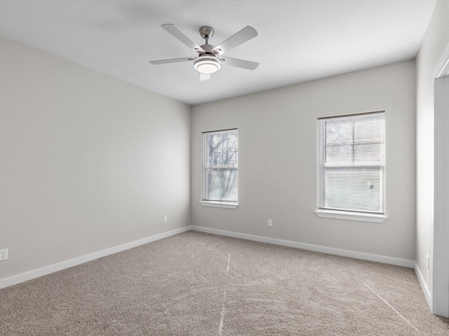 unfurnished room with a wealth of natural light, baseboards, carpet floors, and a ceiling fan