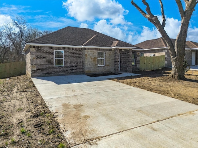 single story home featuring fence, brick siding, stone siding, and a shingled roof