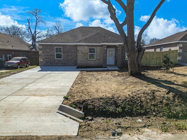 view of front of house featuring fence, brick siding, and a shingled roof