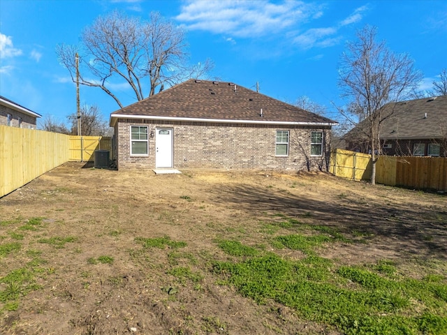 back of property featuring brick siding, central air condition unit, a shingled roof, and a fenced backyard