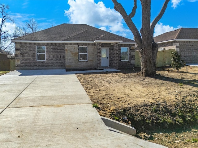 single story home featuring brick siding, a shingled roof, and fence