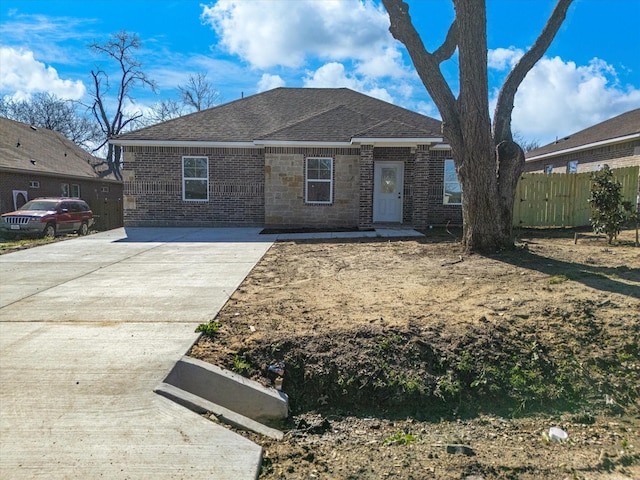 view of front of property with fence, brick siding, and a shingled roof