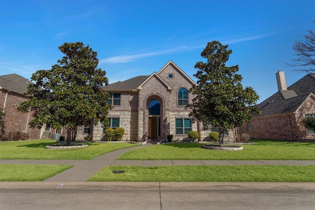 view of front of house featuring a front lawn, brick siding, and stone siding