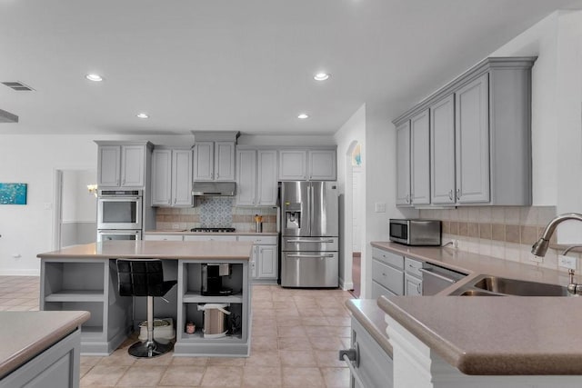 kitchen with visible vents, gray cabinetry, a sink, open shelves, and appliances with stainless steel finishes