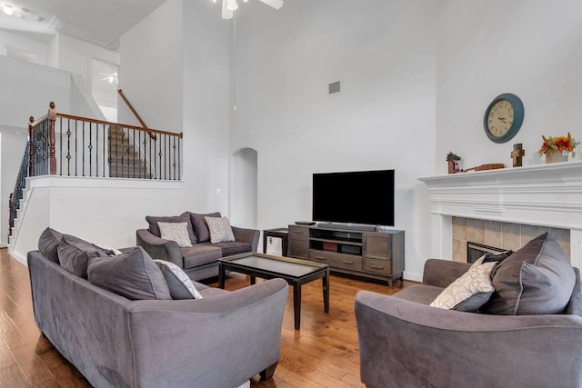 living area with wood finished floors, visible vents, a fireplace, arched walkways, and stairs