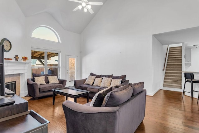 living area with stairway, a fireplace, a ceiling fan, and hardwood / wood-style floors