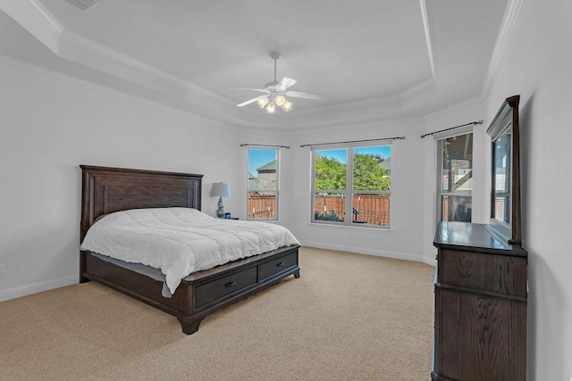 bedroom with a tray ceiling, light carpet, baseboards, and crown molding