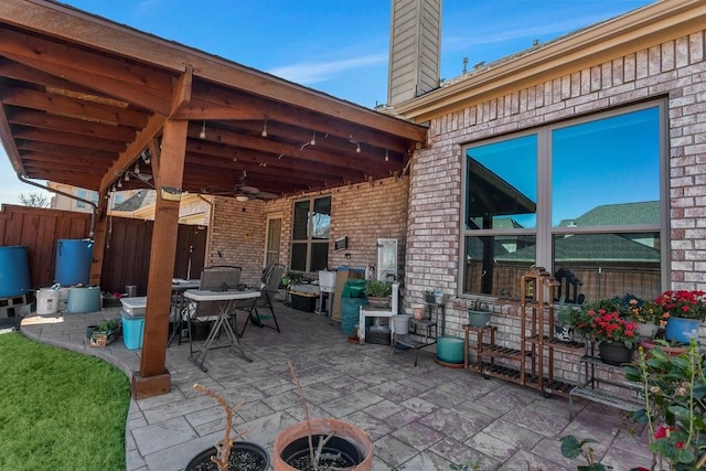 view of patio with outdoor dining space, a ceiling fan, and fence