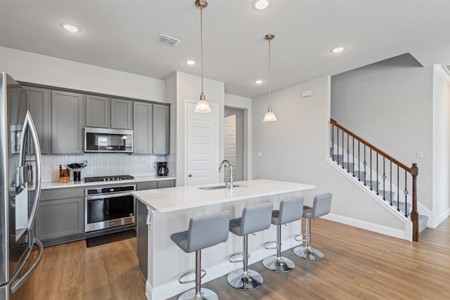 1504 Pleasant Knoll Trl, Aubrey, TX 76227 - kitchen with visible vents, gray cabinetry, a sink, wood finished floors, and appliances with stainless steel finishes