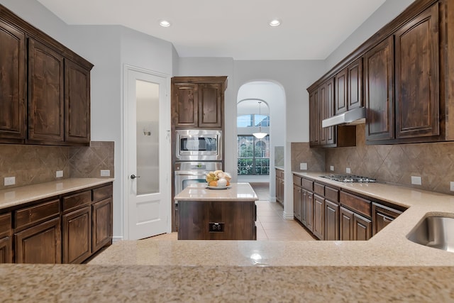 305 Dorset Ct, Roanoke, TX 76262 - kitchen featuring stainless steel appliances, dark brown cabinetry, light stone counters, tasteful backsplash, and recessed lighting