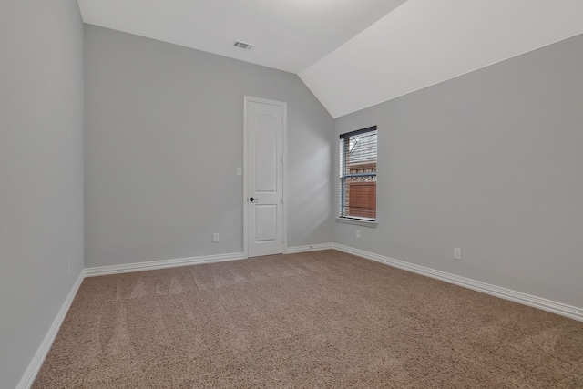 spare room with visible vents, carpet floors, baseboards, and vaulted ceiling