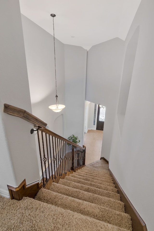 staircase featuring baseboards and high vaulted ceiling