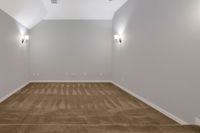 carpeted empty room featuring visible vents, baseboards, and vaulted ceiling