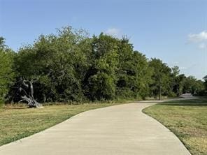 surrounding community featuring concrete driveway and a yard