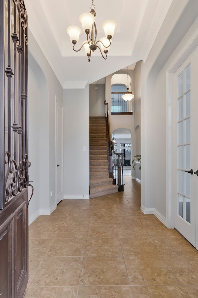 foyer entrance with stairway, arched walkways, an inviting chandelier, crown molding, and baseboards