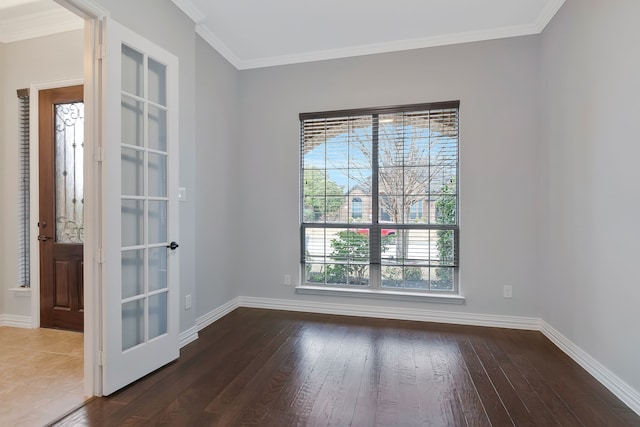 empty room with dark wood-style floors, crown molding, and baseboards