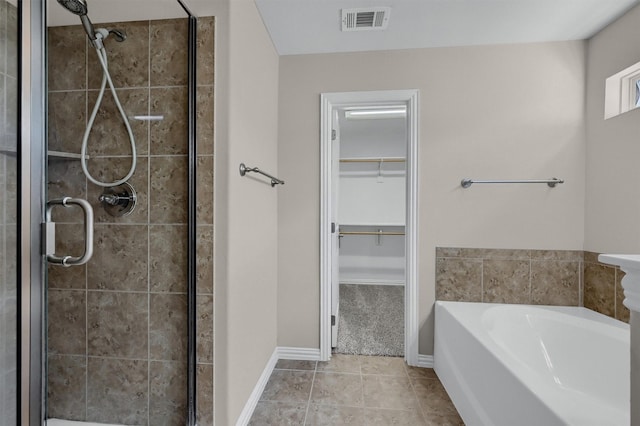 full bathroom with visible vents, a shower stall, a walk in closet, and a garden tub