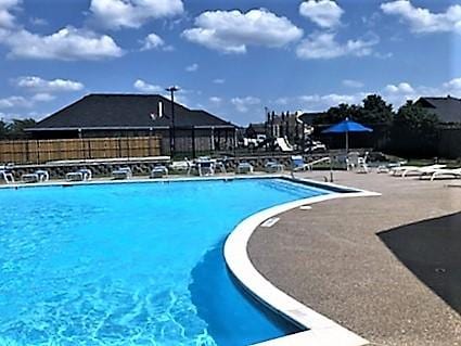 pool with a patio and fence