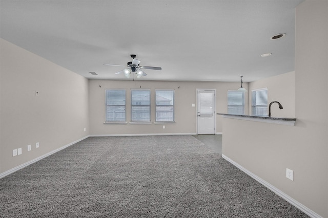 unfurnished living room with visible vents, a ceiling fan, baseboards, and carpet floors