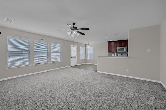 unfurnished living room with visible vents, baseboards, a ceiling fan, and dark carpet