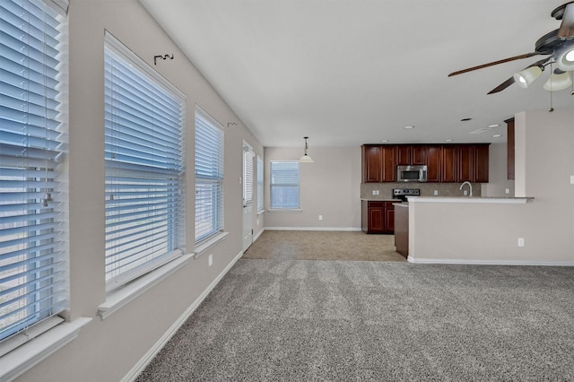 unfurnished living room with a ceiling fan, baseboards, recessed lighting, a sink, and light colored carpet