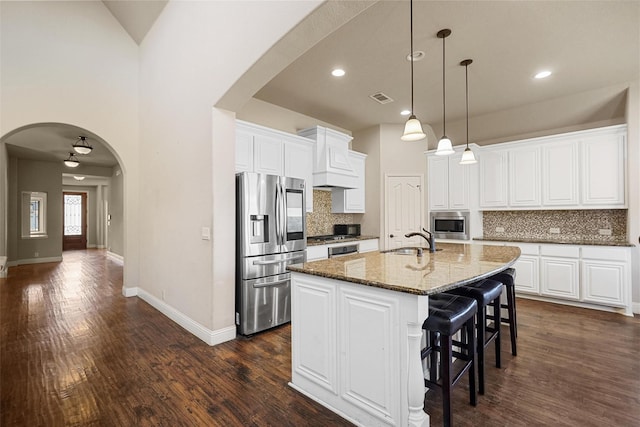 kitchen with a sink, stainless steel appliances, arched walkways, and visible vents